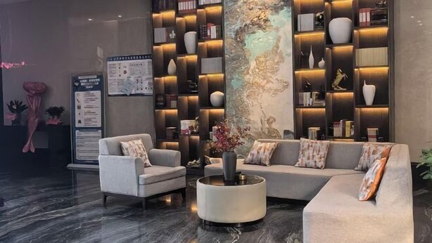 En moderne lobby med en hjørnesofa, to lænestole, et rundt sofabord og et stort, vægmonteret bogreol.