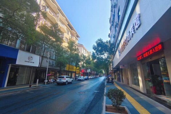Vista de la calle con una hilera de tiendas y un edificio con un cartel que dice 'Hotel'.
