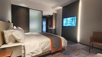 Una habitación de hotel moderna con una cama grande, un escritorio y un televisor en la pared.