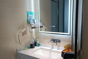 Un bany modern amb un gran mirall, un lavabo blanc i diversos productes de tocador.