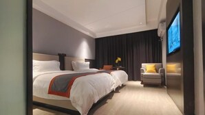 Et moderne hotelværelse med en stor seng, et fjernsyn og en siddeplads med en stol og et lille bord.