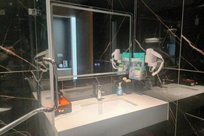 Un bany modern amb un mirall gran, dues dutxes i una zona de tocadors.