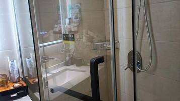 Un baño moderno con cabina de ducha de vidrio, lavamanos a la vista y un perchero para toallas.