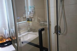 Un bany modern amb una cabina de dutxa de vidre, un lavabo a la vista i un suport per a tovalloles.