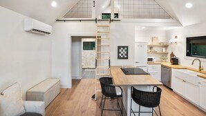 A modern kitchen with a loft bedroom, wooden flooring, and a built-in air conditioning unit. - Uckor's Cottage | Hocking Hills, 5 Acres, Hot Tub (Rockbridge)