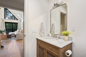 A bathroom with a marble sink, wooden vanity, and a large mirror. - Uckor's Cottage | Hocking Hills, 5 Acres, Hot Tub (Rockbridge)