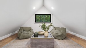 A cozy attic room with a sloped ceiling, a large window offering a forest view, two green bean bags, a coffee table with a vase and a tray, and a patterned rug. - Uckor's Cottage | Hocking Hills, 5 Acres, Hot Tub (Rockbridge)