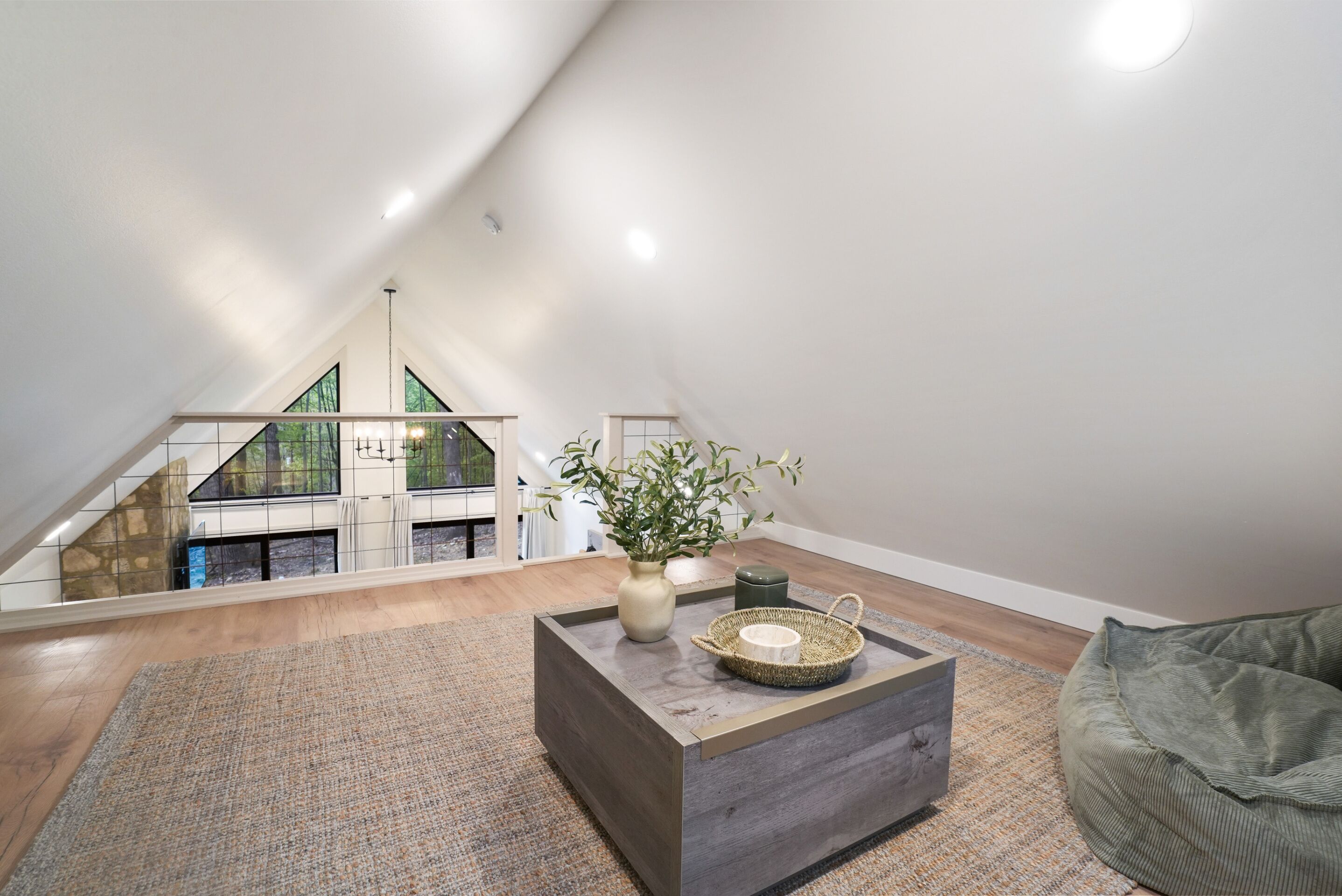Une chambre de style loft moderne, avec un plafond en pente, un plancher en bois, une grande fenêtre et une vue sur un balcon.