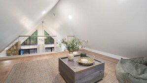 Ein modernes Schlafzimmer im Loft-Stil mit schrägem Dach, Holzboden, großem Fenster und Blick auf einen Balkon.