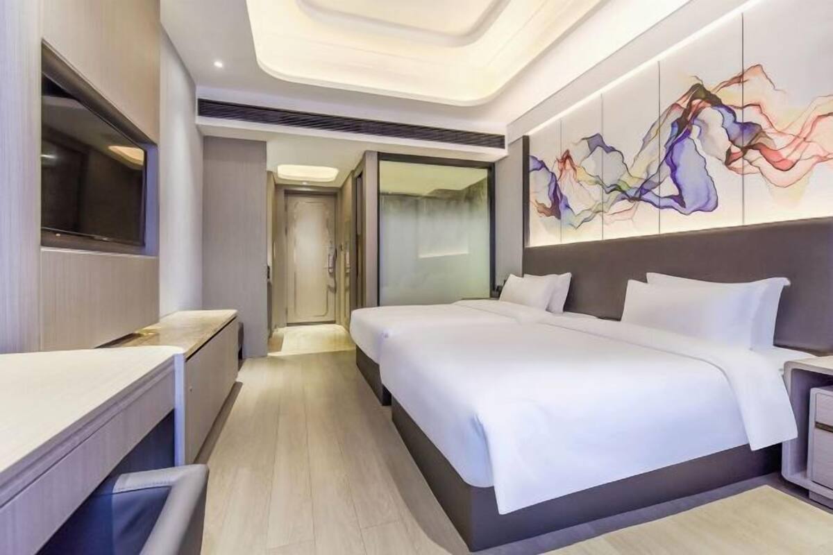 Una habitación de hotel moderna con una cama grande, un escritorio y un televisor.