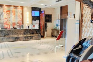 A hotel reception area with a marble counter, a television screen, and a red sign.