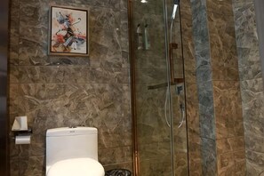 A bathroom with a toilet, a glass shower enclosure, and a marble wall. - Yueyang Kaibinsi Holiday Hotel (Yueyang)