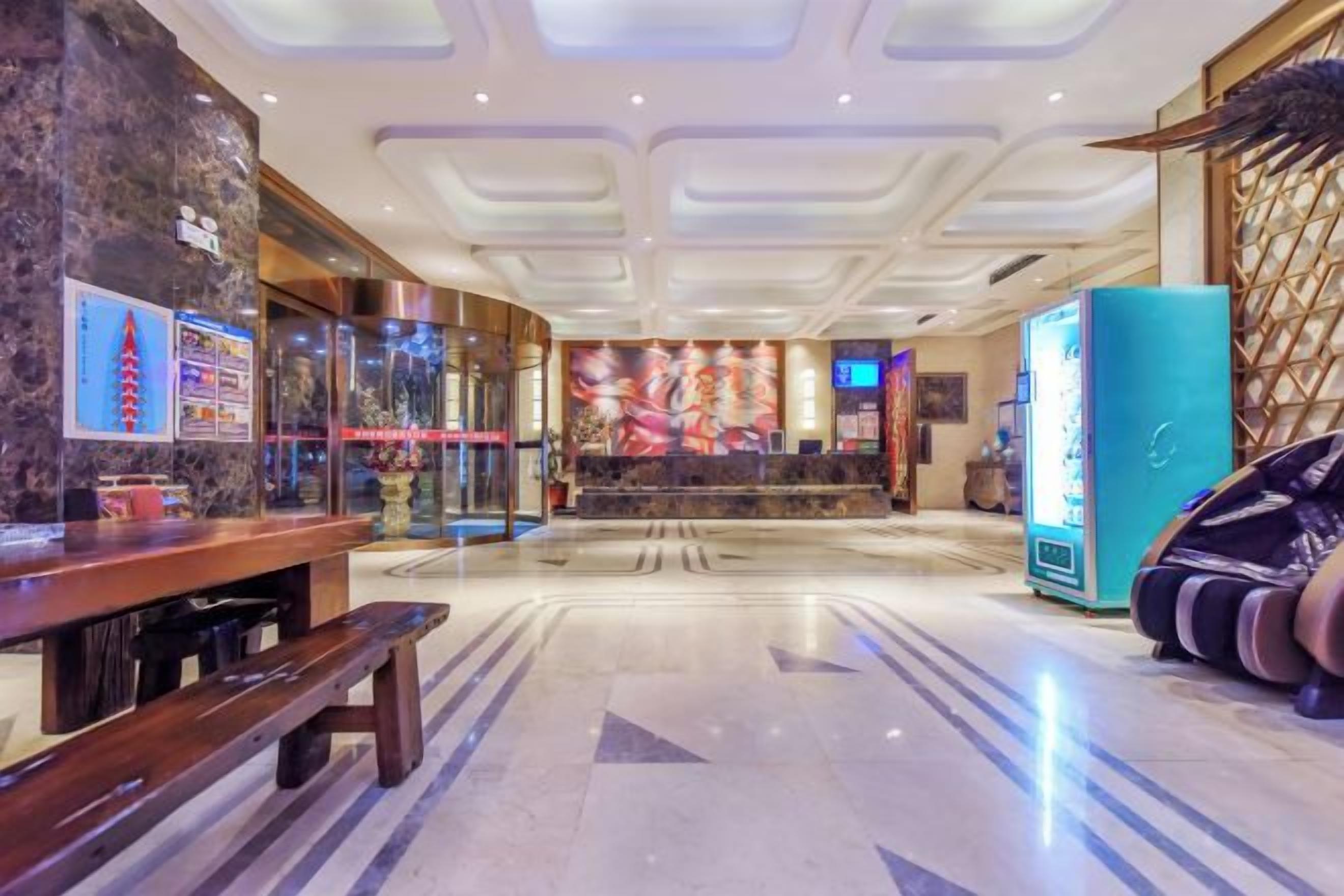 Un vestíbulo de hotel con una recepción, una máquina expendedora y una zona de estar.