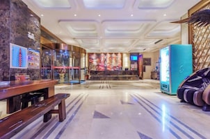 Un vestíbulo de hotel con una recepción, una máquina expendedora y una zona de estar.