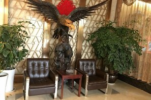 A room with a large eagle statue, two leather chairs, a small table, and potted plants.