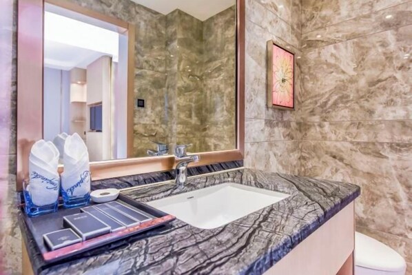 A bathroom with a marble sink, a large mirror, and a framed artwork on the wall. - Yueyang Kaibinsi Holiday Hotel (Yueyang)