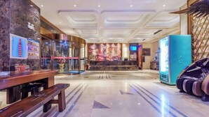 A hotel lobby with a marble floor, a reception desk, massage chairs, and a large mural on the wall.