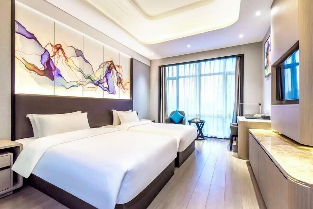 Una habitación de hotel moderna con una cama grande, un escritorio y un televisor.