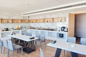 Una cocina moderna con electrodomésticos integrados, un comedor con una mesa larga y sillas, y una isla de cocina.