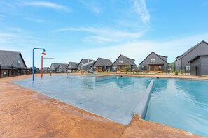 A swimming pool area with a water slide, surrounded by residential buildings with pitched roofs. - Panoramic Table Rock Lake Views with Hot Tub, Games & Free Branson Attraction Tickets (Hollister)