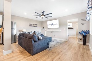 Ein modernes Wohnzimmer mit einer Couch, einem Deckenventilator und einem an der Wand montierten Flachbildfernseher.