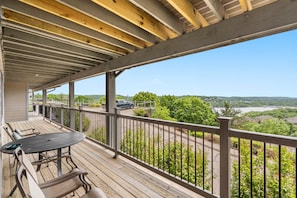 Eine überdachte Terrasse mit Tisch und Stühlen mit Blick auf eine Straße und Grünflächen.