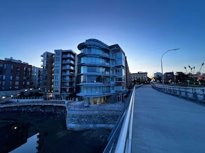 Un edificio moderno de varios pisos con balcones, un puente y un canal.