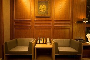 Una stanza con due divani, un tavolino con degli oggetti e una parete in legno con pannello decorativo.