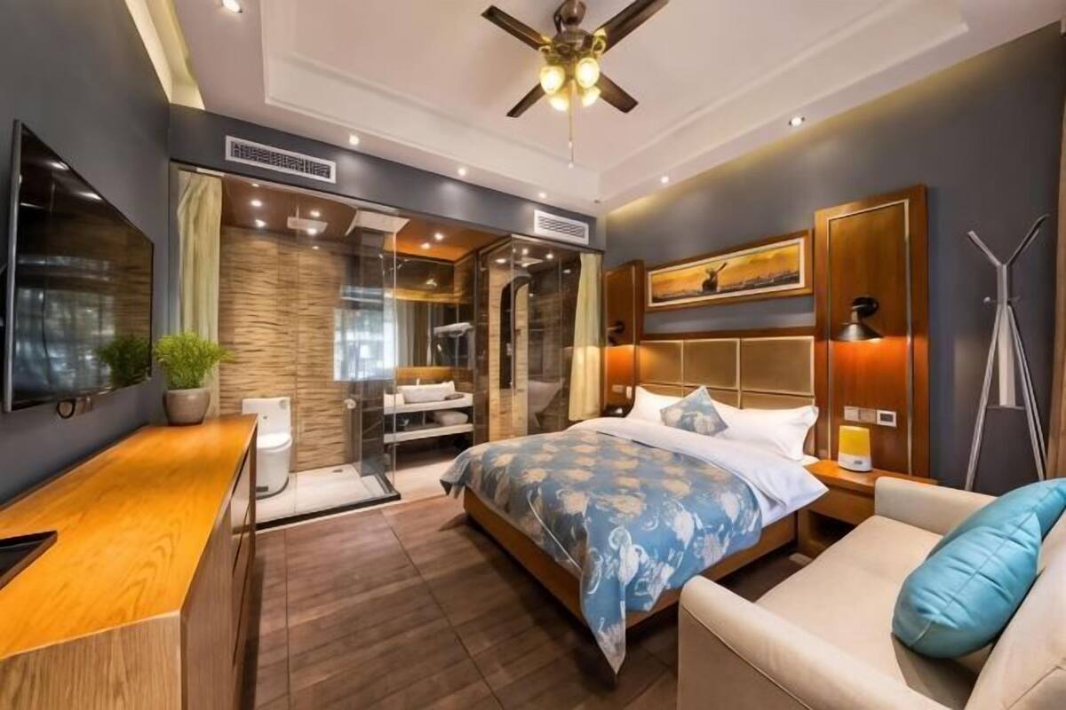 A modern bedroom with a large bed, a bedside table, a TV, a ceiling fan, and a walk-in closet.