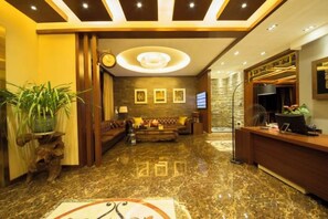 A hotel lobby with a reception desk, seating area, and a large plant. - Chengli Chengwai Inn (Lijiang)