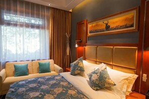 A hotel room with a bed, a sofa, a painting on the wall, and a window with curtains. - Chengli Chengwai Inn (Lijiang)