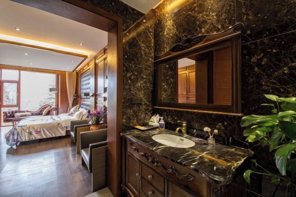 Un bany luxós amb un lavabo de marbre, mobles de fusta fosca i un mirall gran.