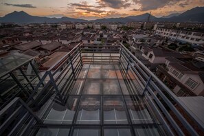 A rooftop terrace with a glass floor, surrounded by traditional buildings, offering a view of the cityscape and mountains. - Chengli Chengwai Inn (Lijiang)