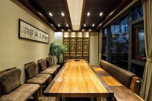 A conference room with a long wooden table, cushioned seating, and traditional decor.