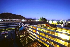 Une terrasse sur le toit offrant une vue sur le paysage urbain et les montagnes au crépuscule.