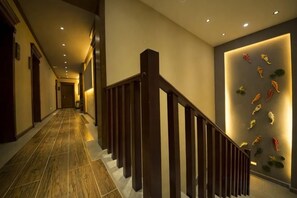 A hallway with a wooden staircase, a wall with decorative fish, and a tiled floor. - Chengli Chengwai Inn (Lijiang)