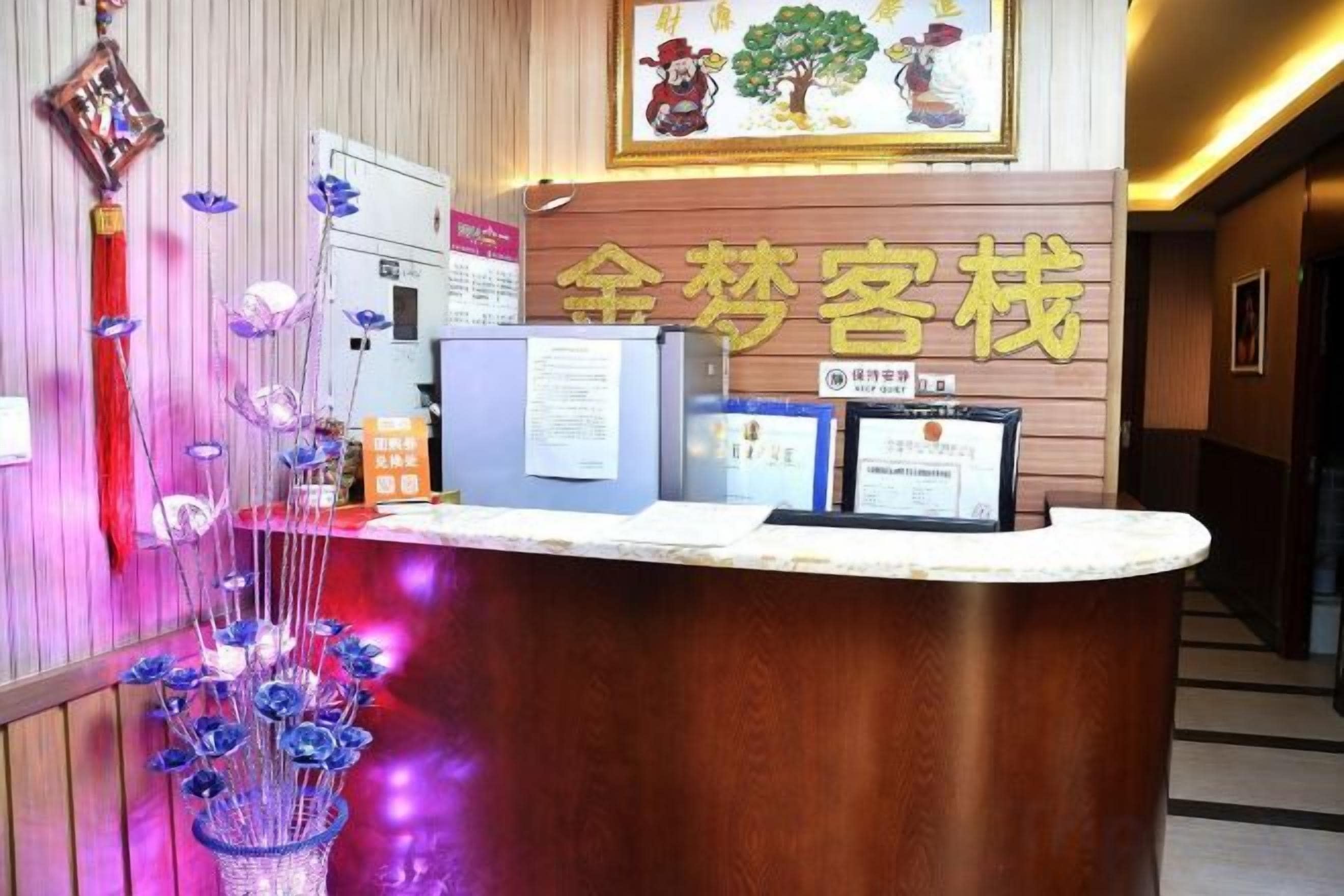 A reception desk with a wooden finish, a framed sign above it, and a wall-mounted information board.
