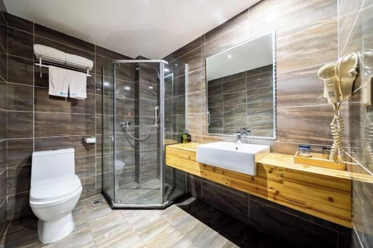A modern bathroom with a glass-enclosed shower, a white toilet, and a wooden vanity with a sink and mirror.