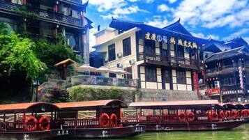 A traditional building with a sign, boats with red decorations, and a clear sky.