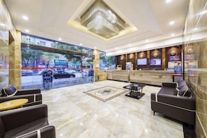 A hotel lobby with a reception desk, seating area, and a large window overlooking the street. - Xinyuan Hotel (Xiushan Bus Terminal) (Xiushan County)