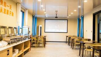 A conference room with tables, chairs, a projector screen, and a whiteboard.