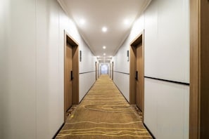 A hotel hallway with carpeted floors, doors on both sides, and a light-colored ceiling. - Xinyuan Hotel (Xiushan Bus Terminal) (Xiushan County)