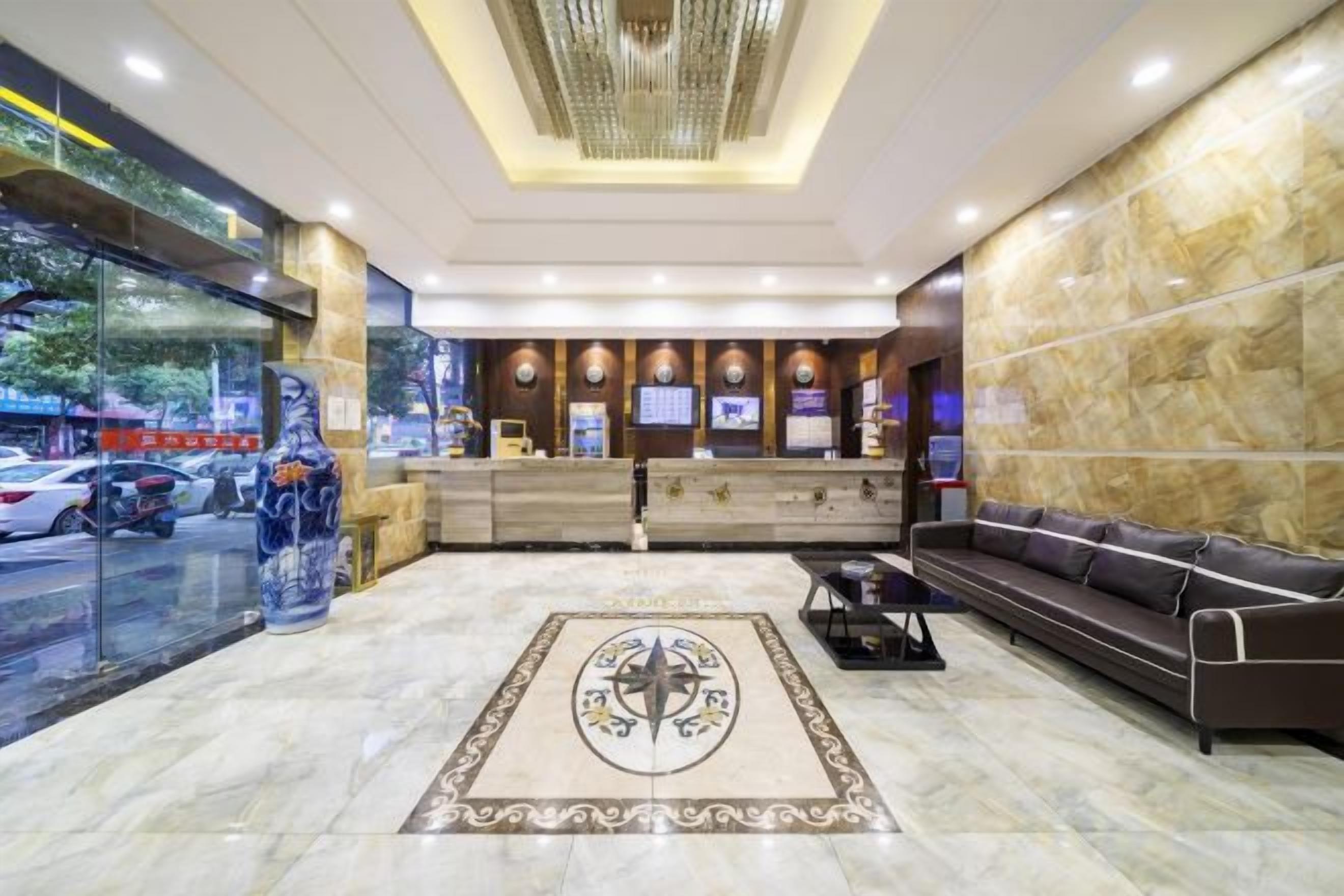 A hotel lobby with a reception desk, seating area, and a decorative rug.