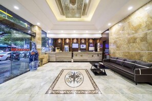 A hotel lobby with a reception desk, seating area, and a decorative rug. - Xinyuan Hotel (Xiushan Bus Terminal) (Xiushan County)