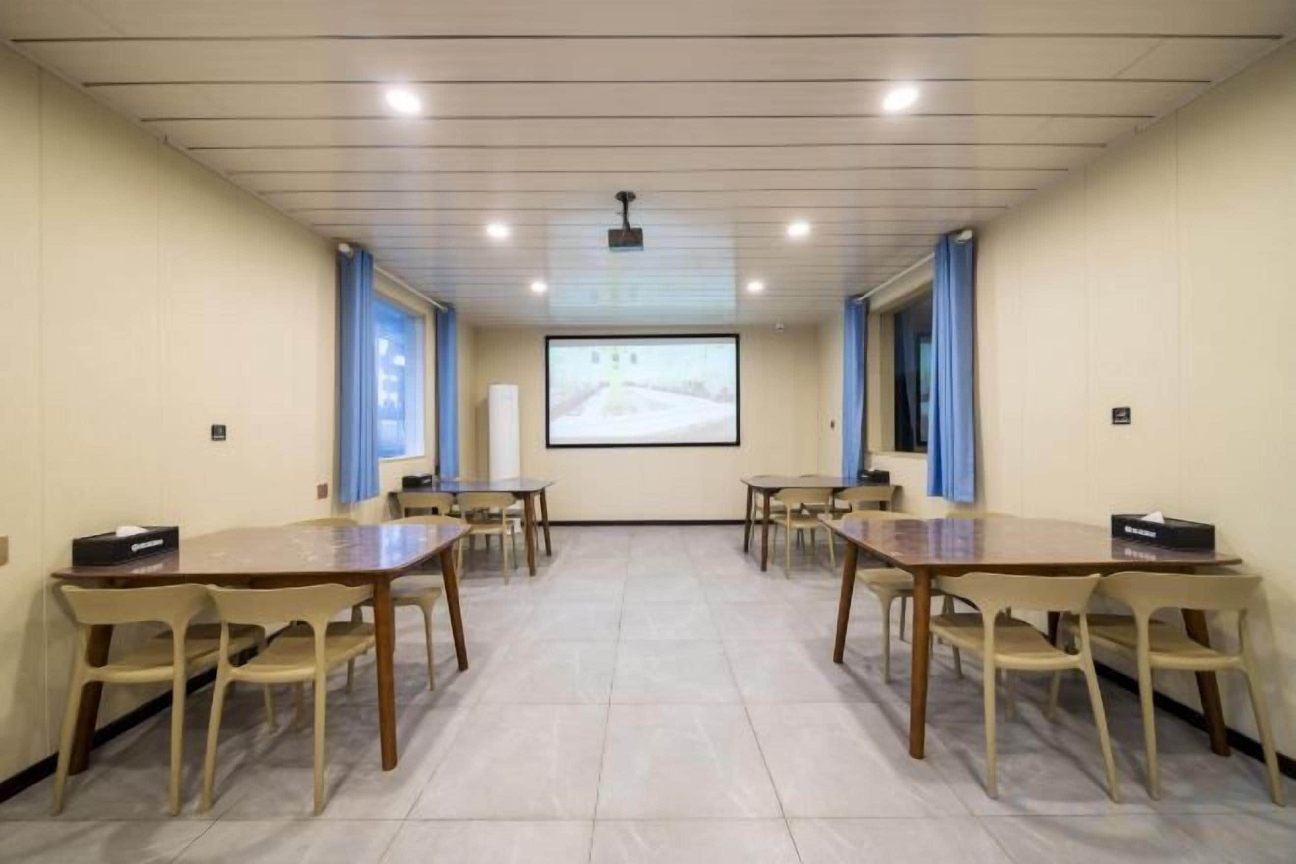 A conference room with a projector screen, tables, and chairs.