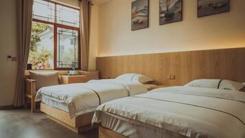 Una camera d'albergo con due letti, una testiera in legno, una scrivania e una finestra con tende.