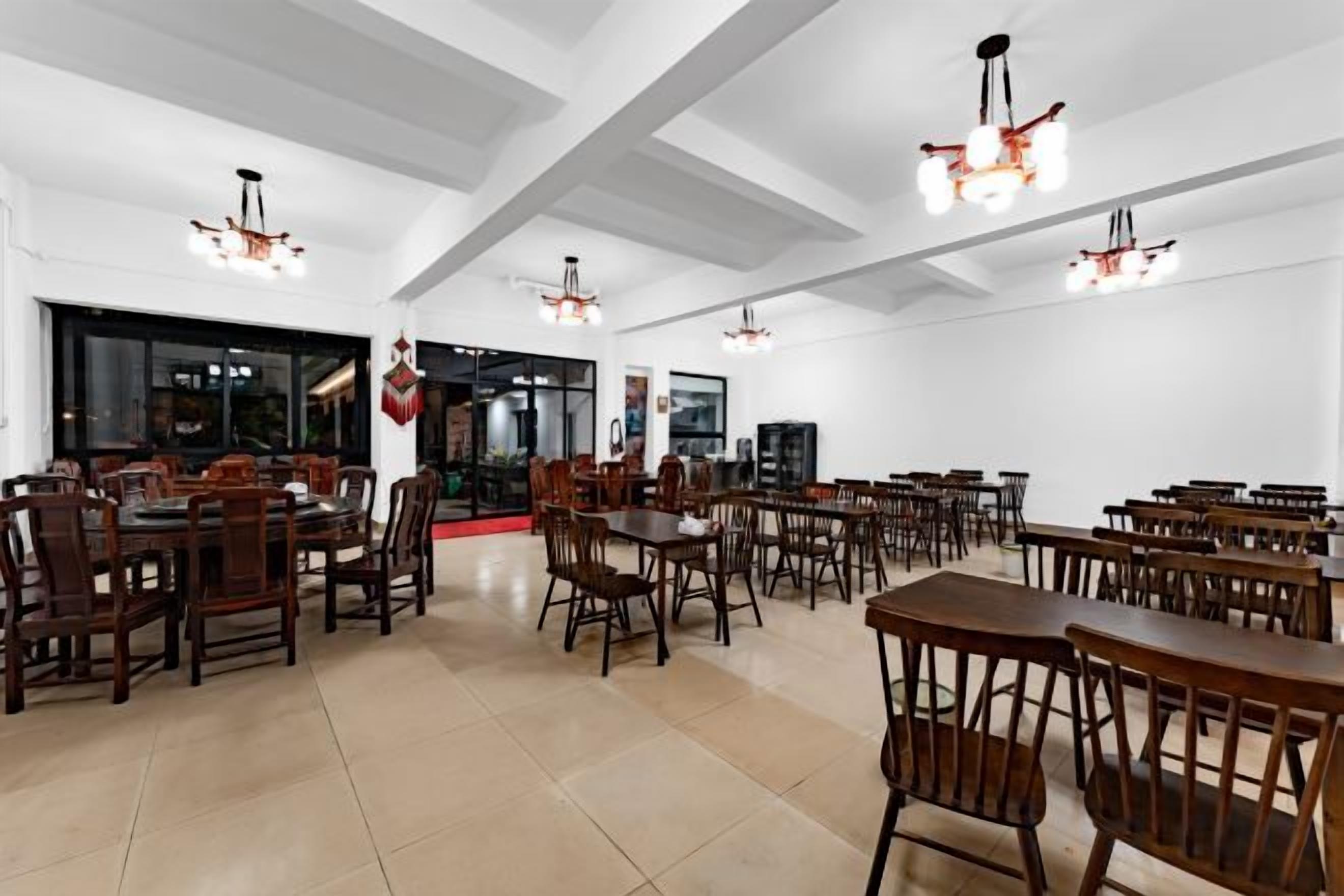 Un'ampia sala da pranzo con numerosi tavoli e sedie, soffitti alti e lampadari.