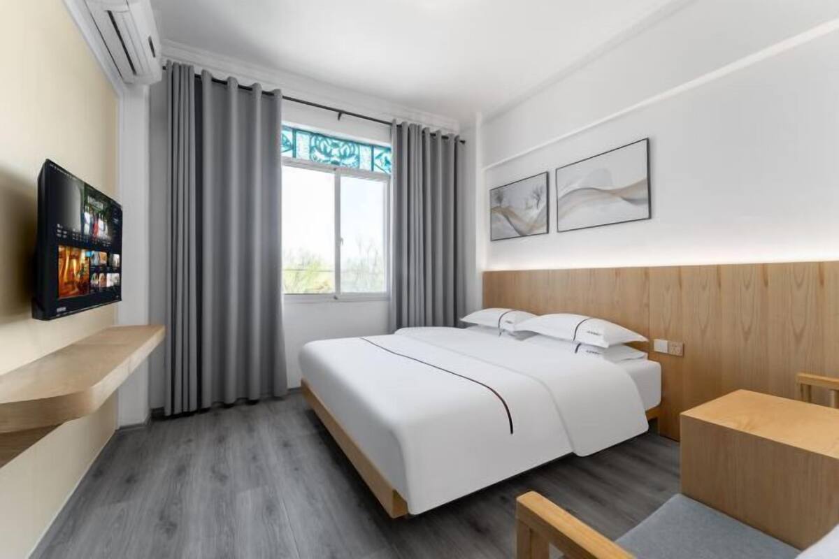 Ein modernes Hotelzimmer mit einem Bett, einem Schreibtisch und einem Fernseher.