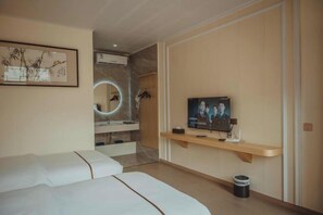 A modern hotel room with a large bed, a TV on a wooden shelf, a bathroom with a mirror, and a small trash bin.
