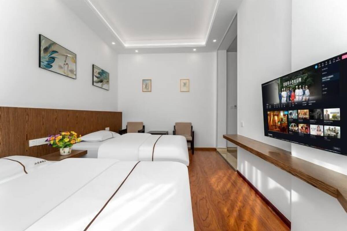 Ein Hotelzimmer mit zwei Betten, einem Fernseher und Bildern an den Wänden.
